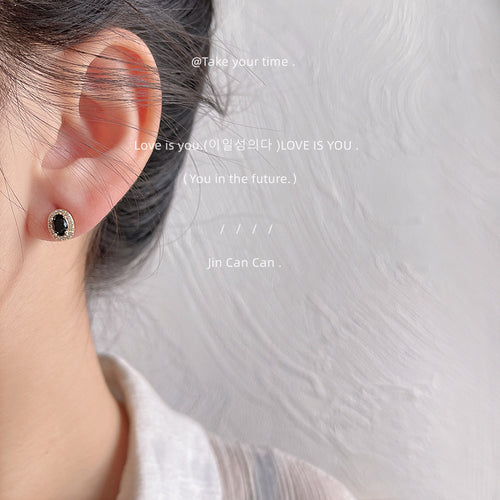 Gold-tone black-oval clear-halo mini studs shown worn on an ear.