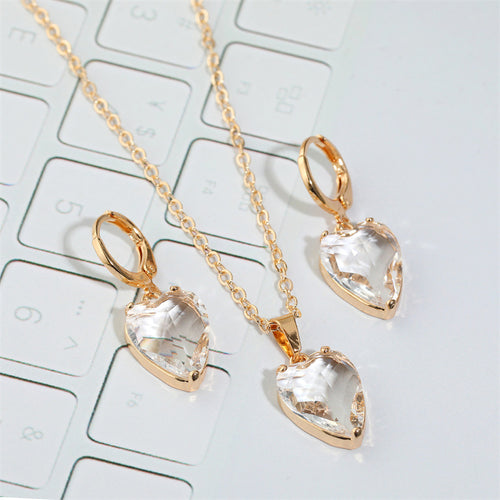Clear heart crystal hoop earrings and pendant necklace on white keyboard