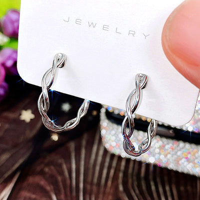 Front view of textured open hoop earrings in silver tone with clear crystal details