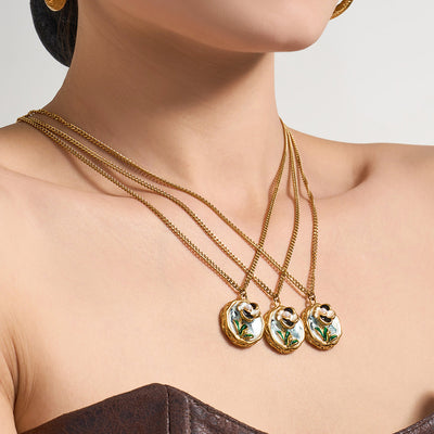 Model wearing three gold enamel floral disc pendant necklaces layered at the neckline