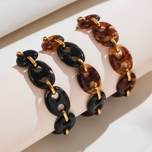 On-wrist view of black mixed and amber resin link bracelets in main image 1.