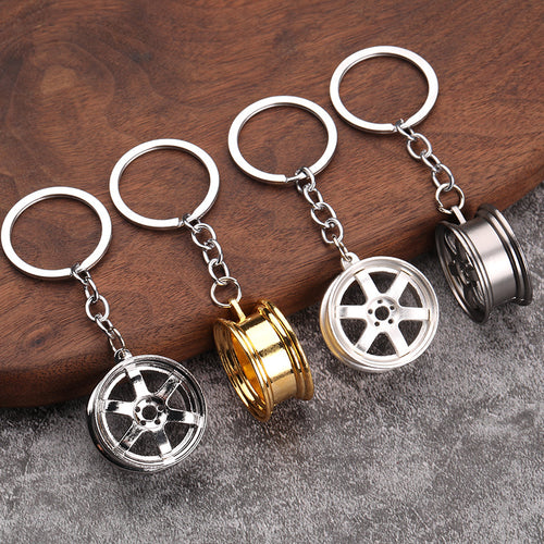 Four six-spoke wheel keychains shown from front and side angles on a wooden surface.