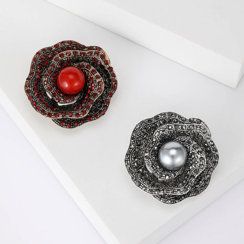 Red gold and gunmetal gray rhinestone rose brooches on white steps